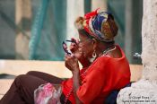 Travel photography:Old woman applying make-up on a street in Havana Vieja, Cuba