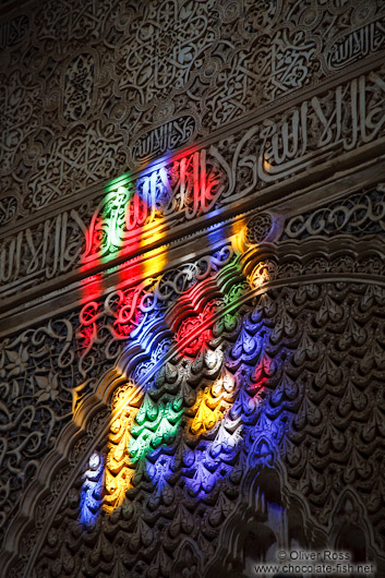 Sunlight enters through a coloured window into an ornate arabesque alcove of the Nazrin palace in the ranada Alhambra
