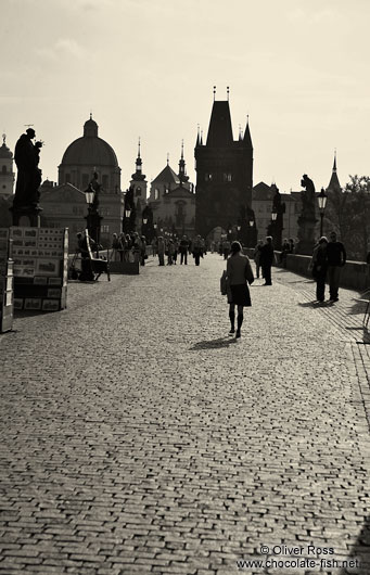 People on Charles Bridge with the Old Town skyline (with a dark yellow tint)