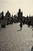Travel photography:People on Charles Bridge with the Old Town skyline (with a dark yellow tint), Czech Republic