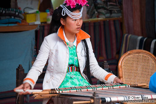 Girl with traditional Naxi dress weaving in Lijiang