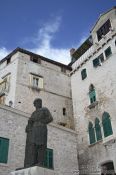 Travel photography:Houses in Sibenik with the bronze statue of Dalmatinac by Ivan Mestrovic, Croatia