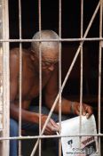 Travel photography:Man reading the newspaper behind bars in Havana Vieja, Cuba