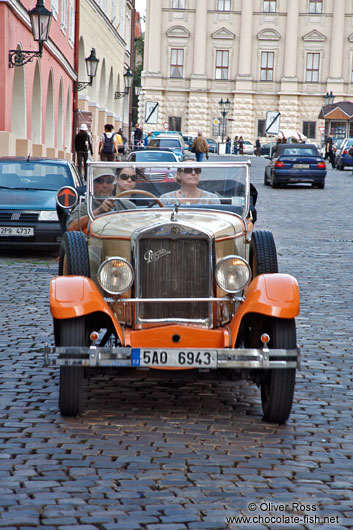 Tourists on a tour in a classic vintage car inside Prague Castle