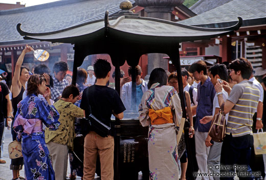 Rubbing in the incense for good luck at Senso-ji temple in Tokyo Asakusa