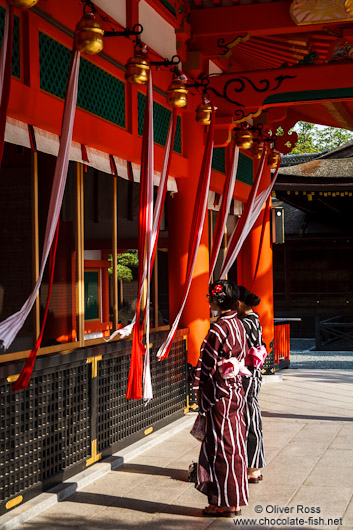 Two girls in Kimono pray at  Kyoto´s Inari shrine