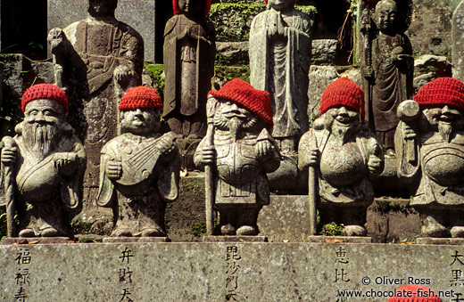Statues with hats outside a forest shrine
