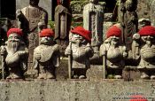 Travel photography:Statues with hats outside a forest shrine, Japan