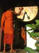 Travel photography:Buddhist monk novice performing the drumming ritual just before sunset, Laos