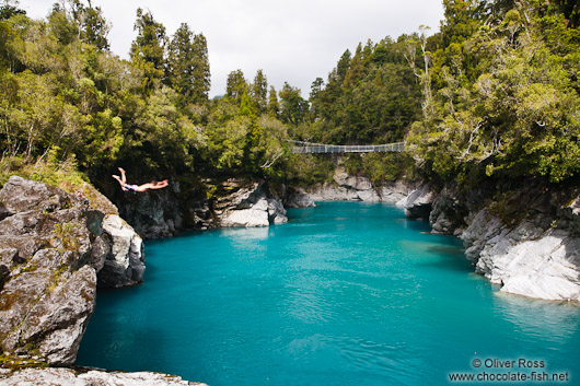 A swimmer jumps into the turquoise glacier water in Hokitika Gorge