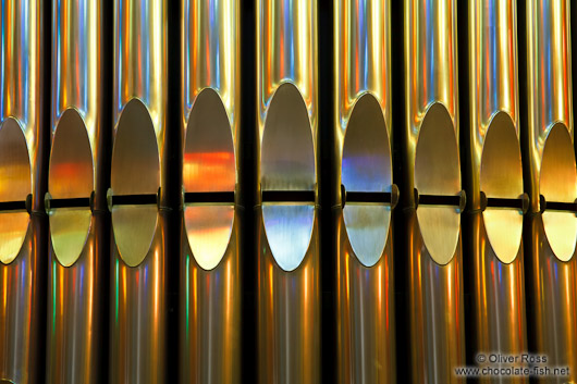 Colourful light from the stained glass windows is reflected off the organ pipes in the Sagrada Familia