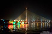 Travel photography:Lit tourist boat with suspension bridge across Bangkok´s Mae Nam Chao Phraya river, Thailand