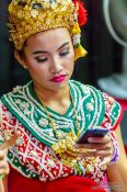Travel photography:Girl in traditional Thai dress with mobile phone, Thailand