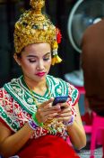 Travel photography:Girl in traditional Thai dress with mobile phone, Thailand