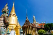 Travel photography:Stone guardian and golden stupa at Wat Phra Kaew, the Bangkok Royal Palace, Thailand