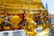 Travel photography:Golden Kinnara and demon sculptures at Wat Phra Kaew, the Bangkok Royal Palace, Thailand
