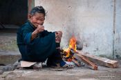 Travel photography:Hmong woman with small fire in a Sapa back yard, Vietnam